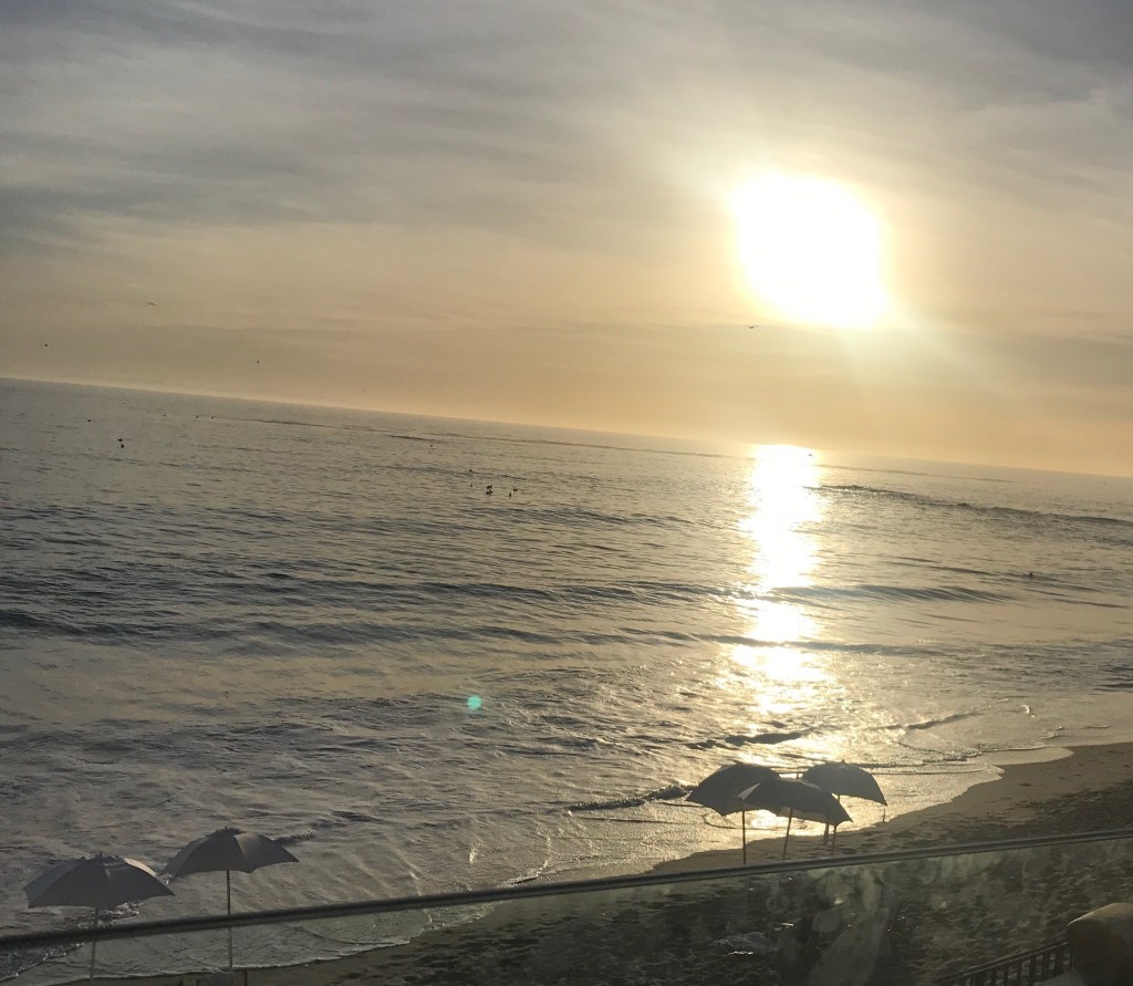 sunset on the ocean, sandy shore with umbrellas